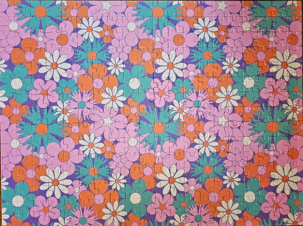 A repeating pattern of stylized, retro-inspired flowers in bright orange, light pink, turquoise, and white.