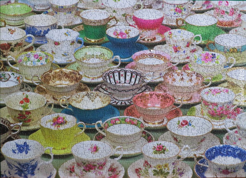 A dense, colorful collection of vintage porcelain teacups and saucers in various floral patterns and solid hues.