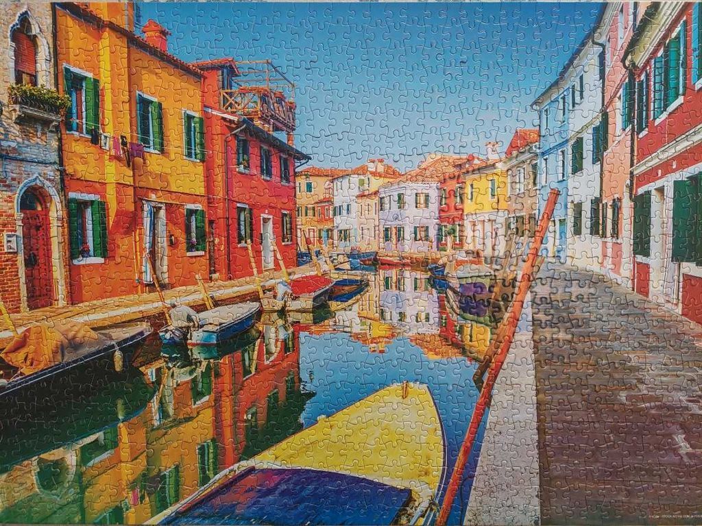 Vibrant, multi-colored buildings reflected in a tranquil canal on the island of Burano, Italy.