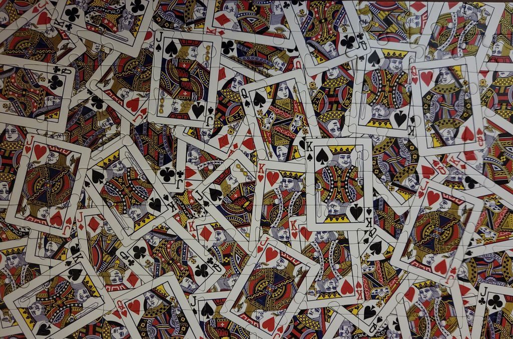 A dense, overlapping collage of classic playing card faces including Kings, Queens, and Jacks.