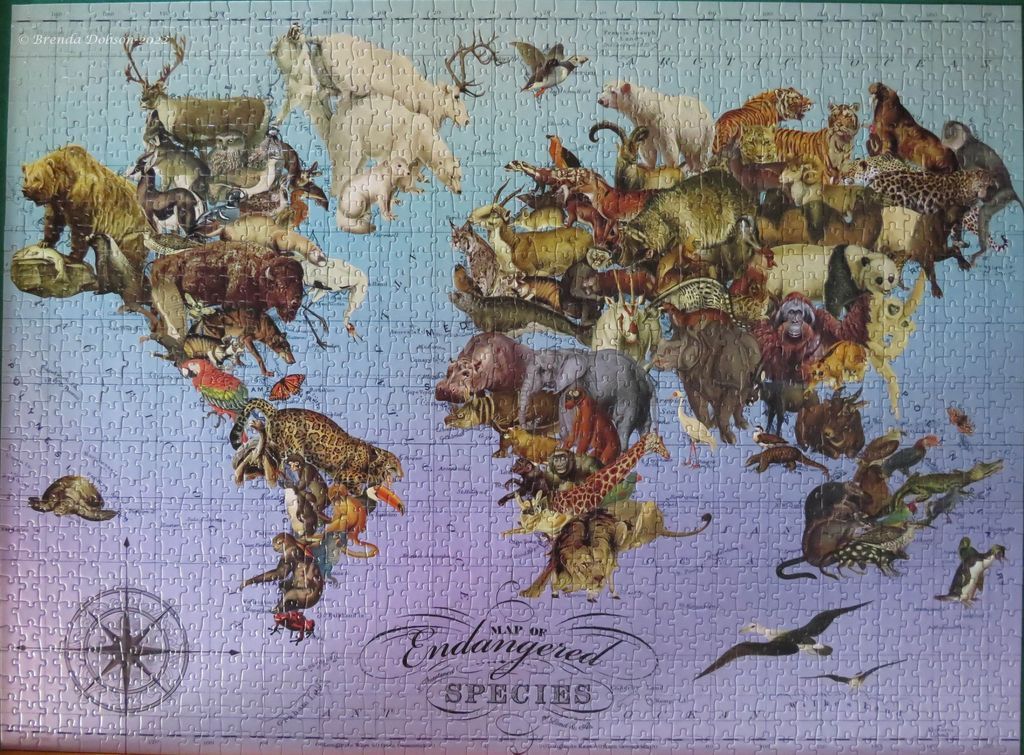 A world map illustration composed of various endangered animals against a pale blue and purple background.