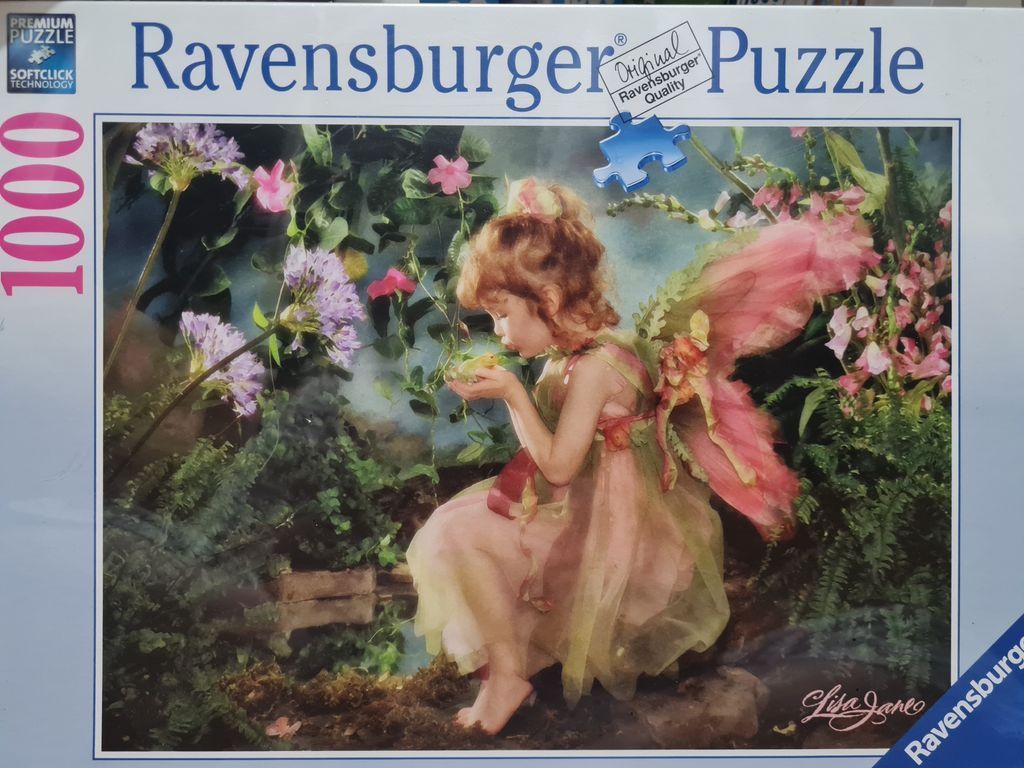 A young girl dressed as a fairy with pink wings, holding a tiny frog in her cupped hands amidst a lush flower garden.