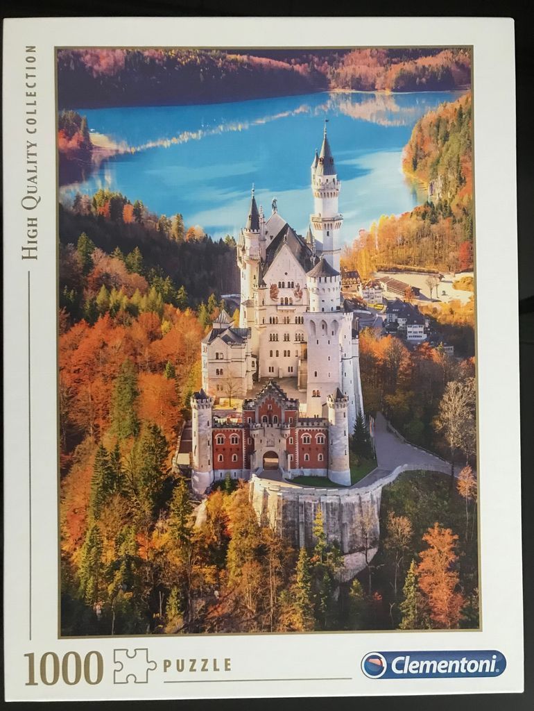 Aerial view of Neuschwanstein Castle in autumn with a bright blue lake in the background.