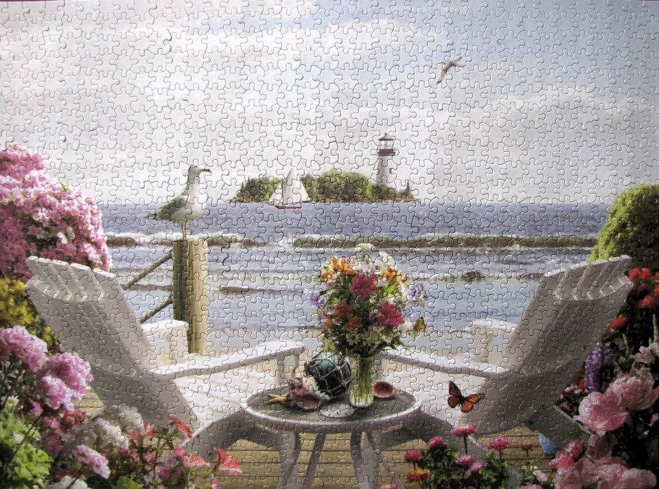 A peaceful seaside scene with two white chairs, a flower bouquet, and a lighthouse in the distance.