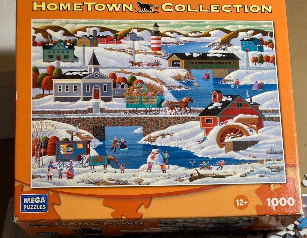 Winter town scene with a red mill, frozen river, covered bridge, and people enjoying snowy activities.