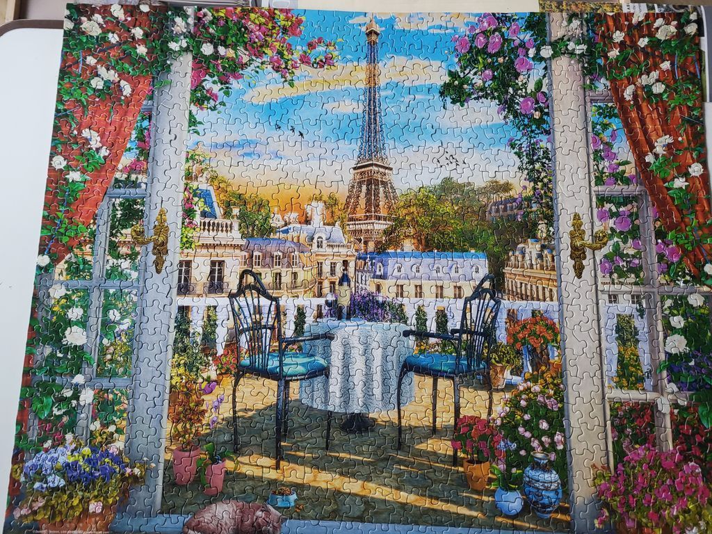 A balcony view of the Eiffel Tower framed by flowers and curtains