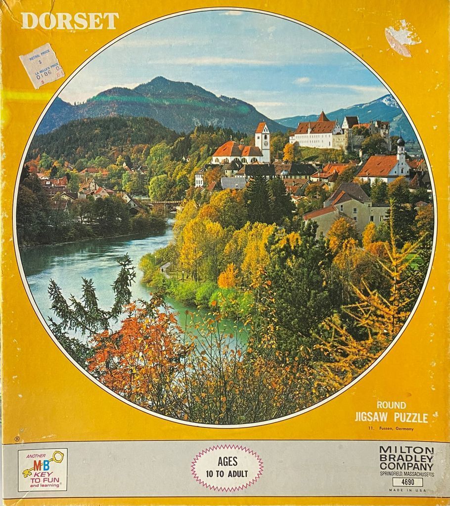 A scenic autumn view of the town of Fussen, Germany, nestled beside a river with mountains in the background.