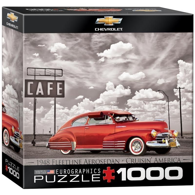 A vintage red 1948 Chevrolet Fleetline Aerosedan parked by a cafe sign against a cloudy sky.
