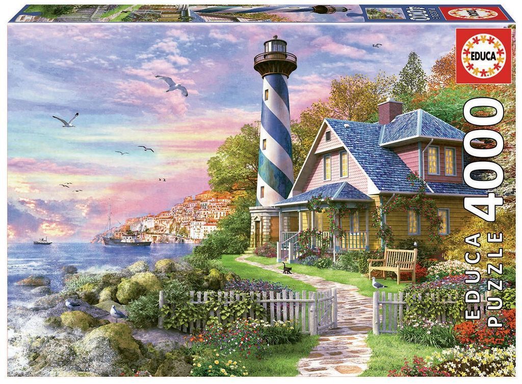 A lighthouse with blue and white stripes standing next to a yellow house by a coastal town at sunset.