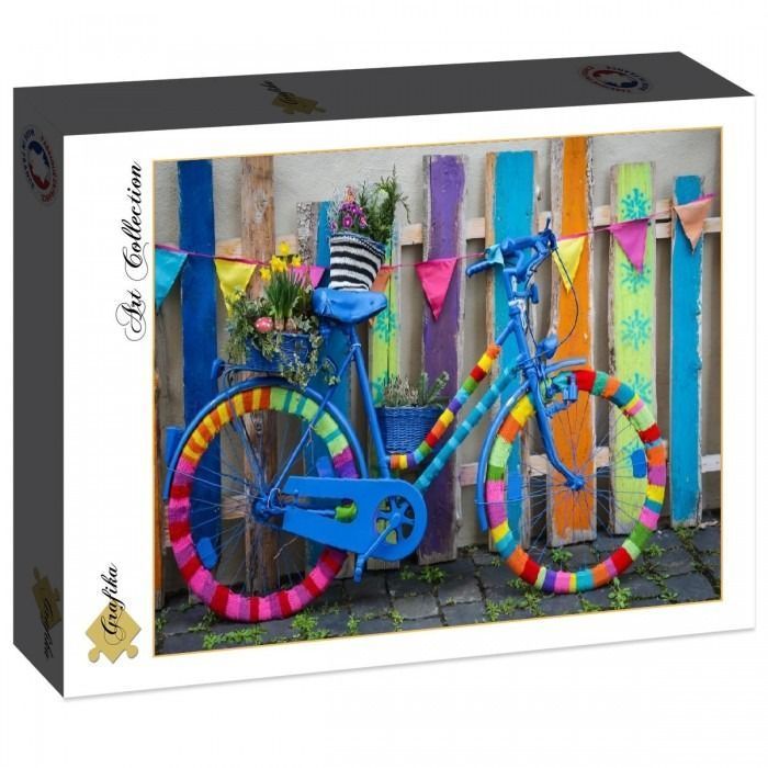 A blue bicycle decorated with colorful yarn covers stands against a rustic fence with bunting.