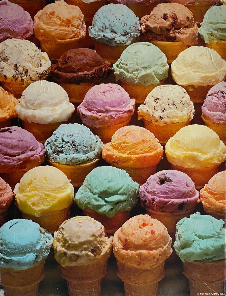An array of colorful ice cream scoops served in waffle cones filling the frame.