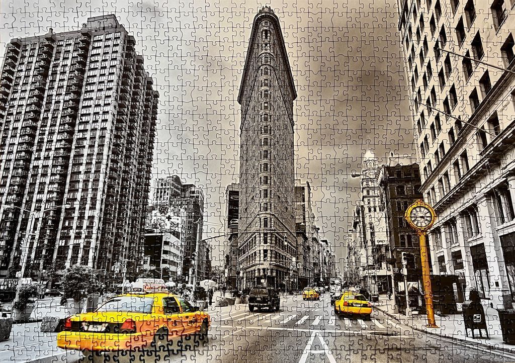 New York City street scene featuring the Flatiron Building and a yellow taxi in sepia tone.