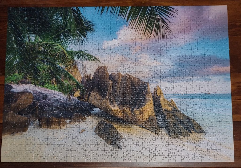 Tropical beach scene with large granite boulders and palm fronds at sunset