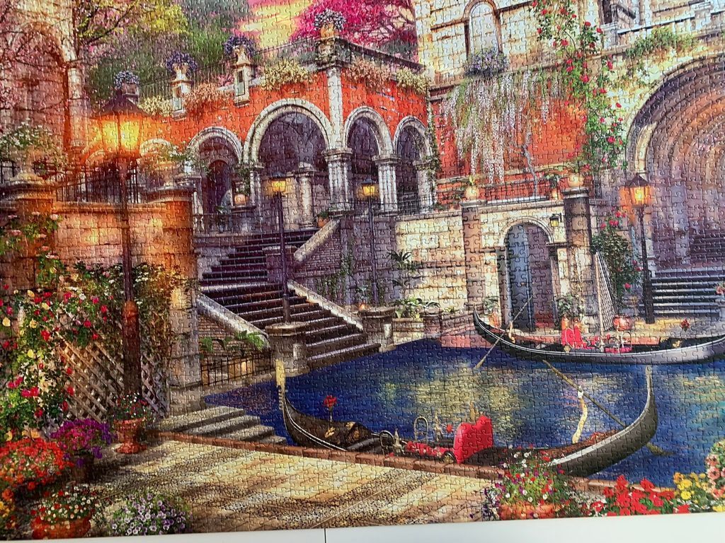 A romantic Venetian scene with gondolas, stone staircases, and glowing lanterns at sunset.