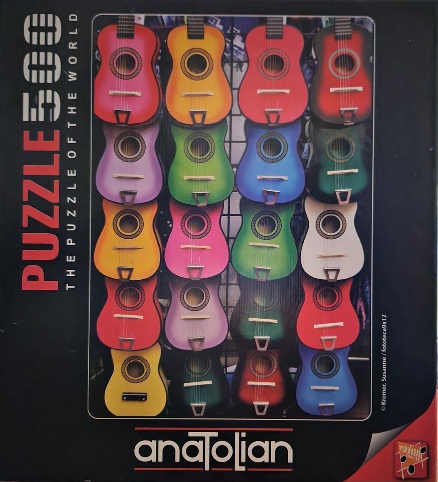 A collection of colorful acoustic guitars hanging in a grid-like display against a black background.