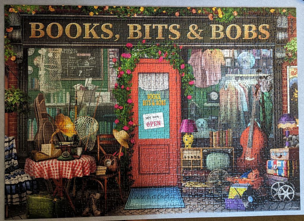 An illustration of a charmingly cluttered shop called Books, Bits & Bobs with a red door and eclectic vintage merchandise.