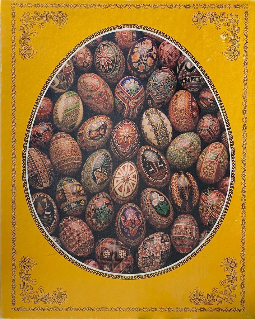 A collection of intricately decorated pysanky Easter eggs arranged within an oval frame on a bright yellow background.