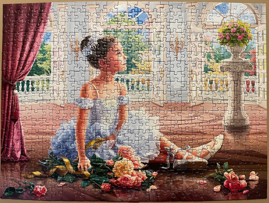 A young girl in a blue ballet dress sitting on a wooden floor in a grand room with large windows and flowers.