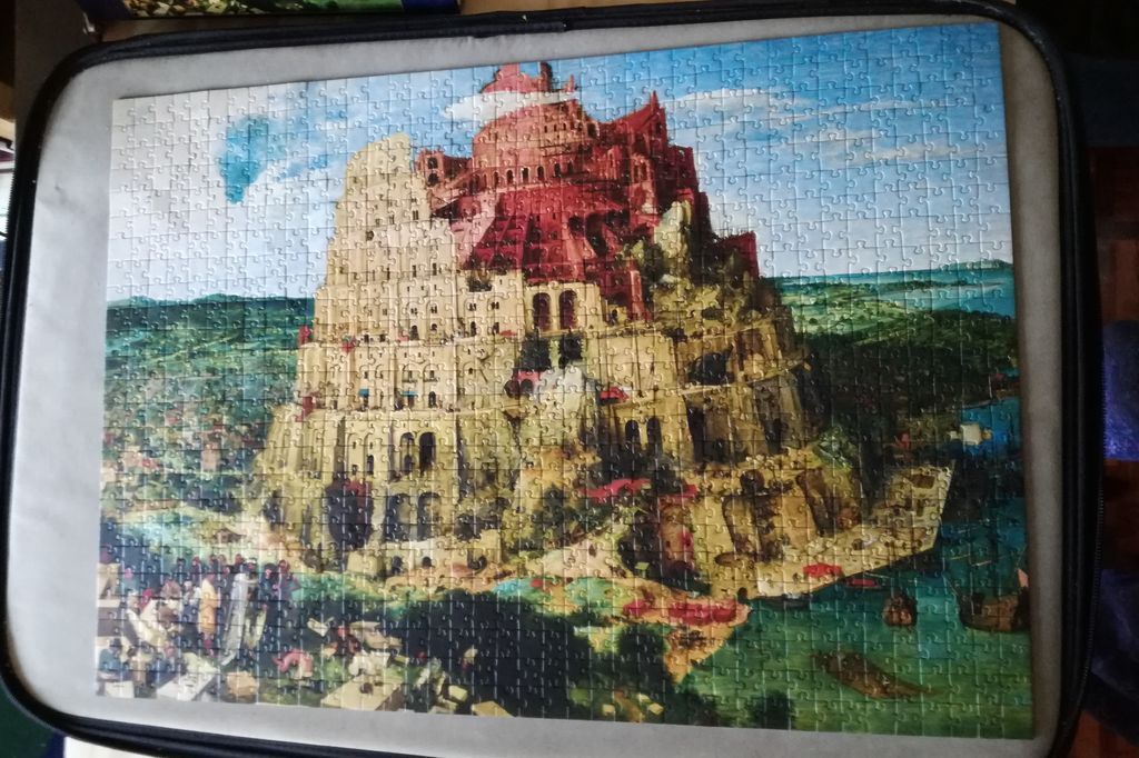 A detailed painting of the Tower of Babel rising above a landscape and a harbor.