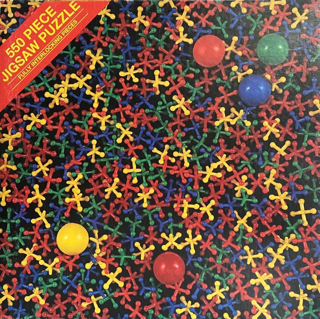 A dense cluster of colorful metal jacks and five smooth, solid-colored balls set against a dark background.