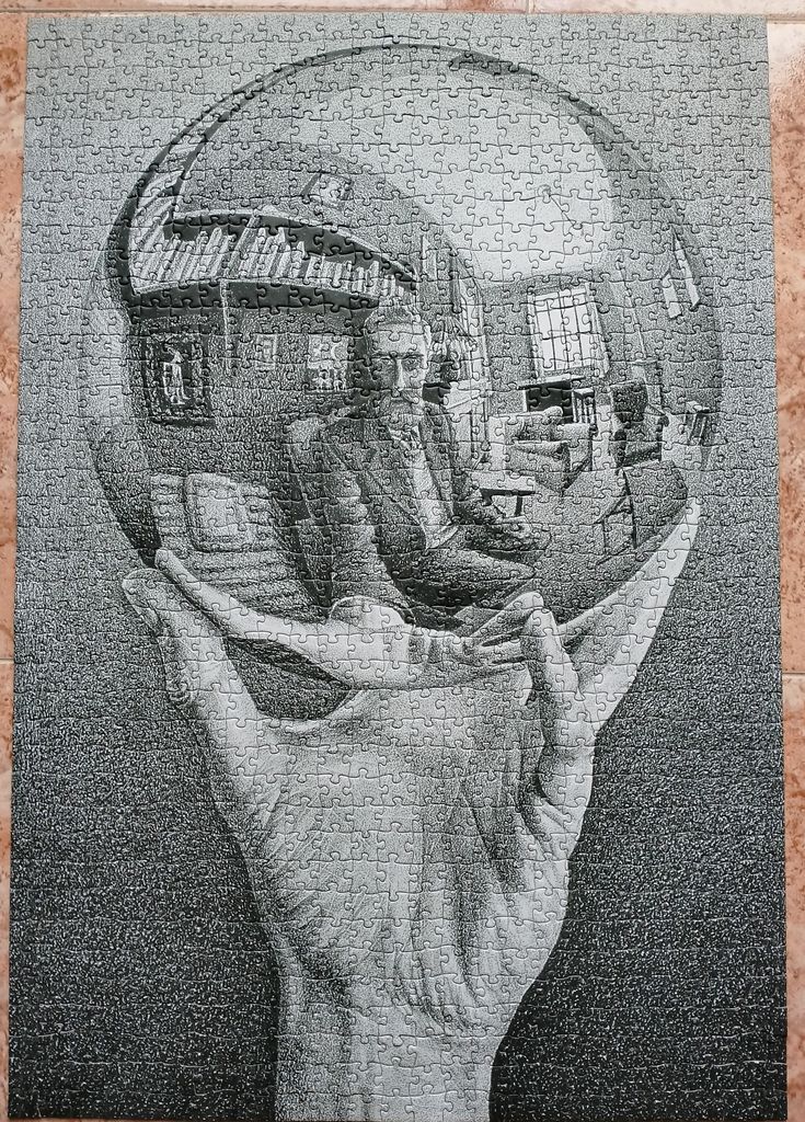 A black and white lithograph of a hand holding a reflective sphere containing a self-portrait.
