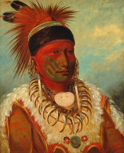 Portrait of a Native American man wearing traditional regalia, a feather headdress, and a bear claw necklace.