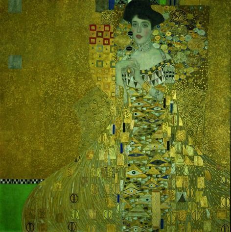 Portrait of a woman wearing a gown adorned with Egyptian-inspired eye motifs and ornate gold geometric patterns.