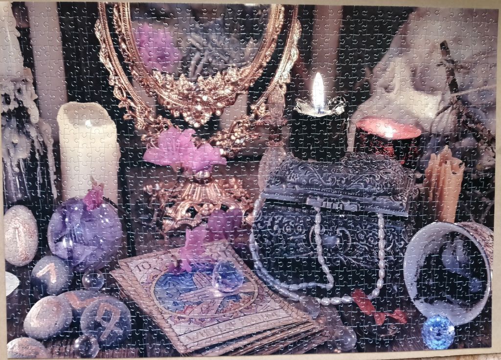 An occult-themed still life featuring a black candle, ornate mirror, tarot cards, and crystals.