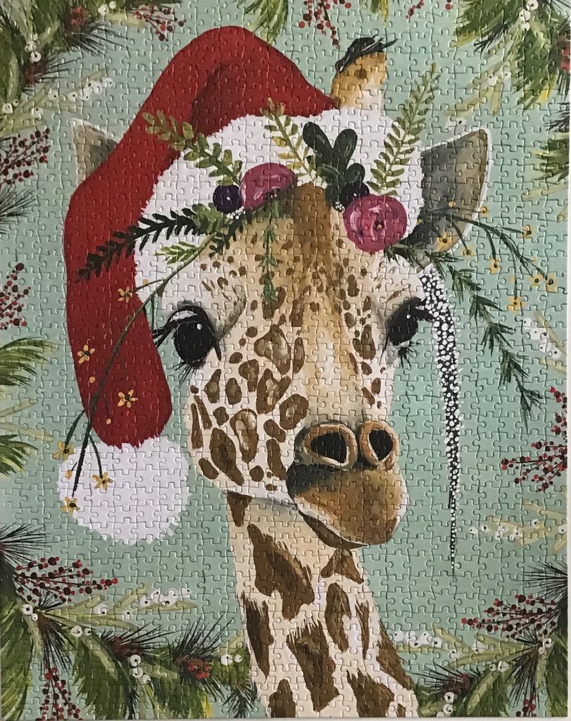 A whimsical illustration of a giraffe wearing a Santa hat and a floral crown against a sage green background.