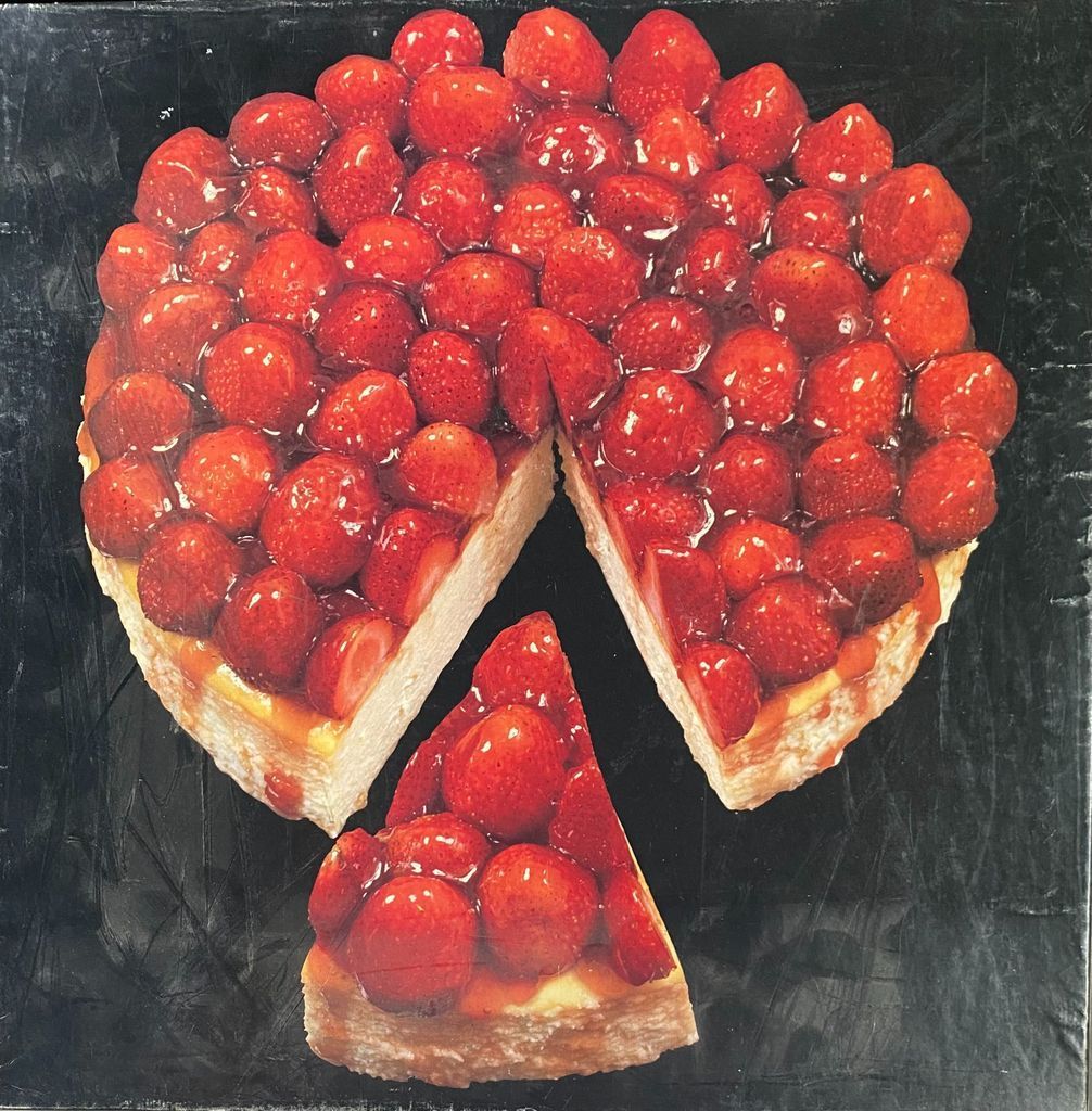 A strawberry cheesecake on a black background with one slice removed.