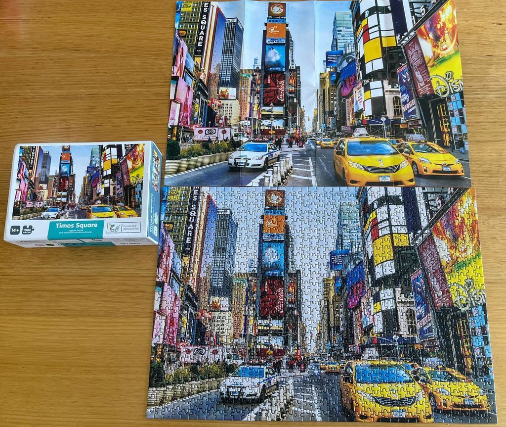A street-level view of Times Square in New York City with yellow taxis and a police car.