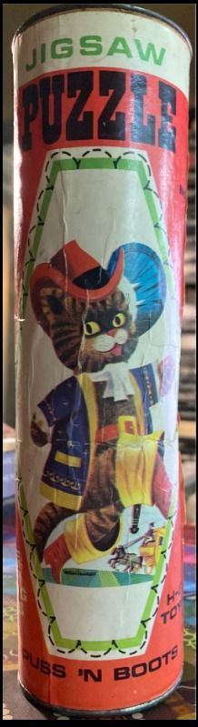 Vintage illustration of Puss in Boots wearing a blue coat, red hat, and yellow boots on a cylindrical container.
