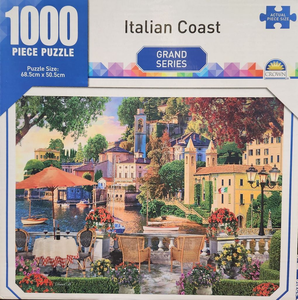 A peaceful Italian seaside terrace with a cafe table, wicker chairs, and a view of a coastal village at sunset.