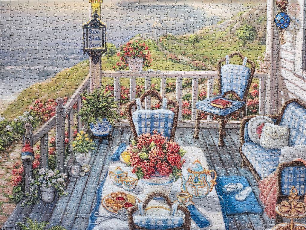 A cozy outdoor porch scene overlooking a rolling green hillside with a table set for tea, painted in a soft, nostalgic style.