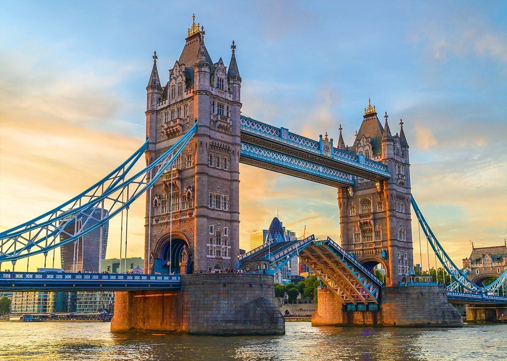 Tower Bridge in London with its bascules partially raised during a sunset sky.