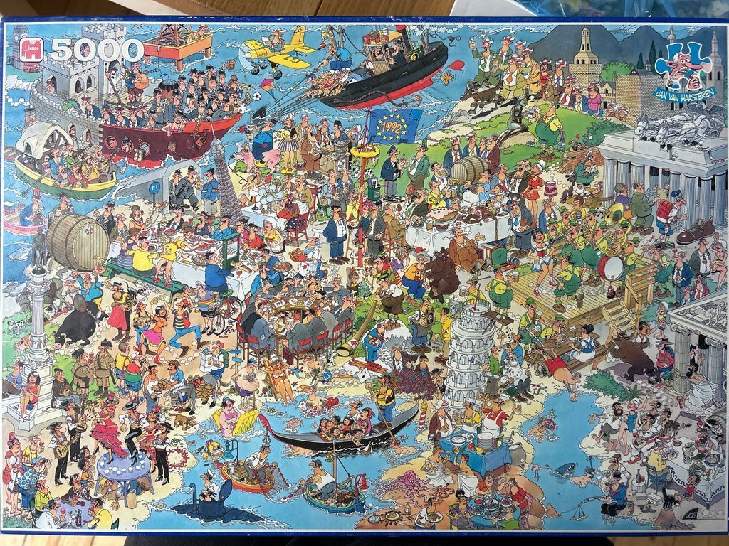 A crowded, humorous cartoon illustration featuring a chaotic European-themed festival scene with hundreds of characters.