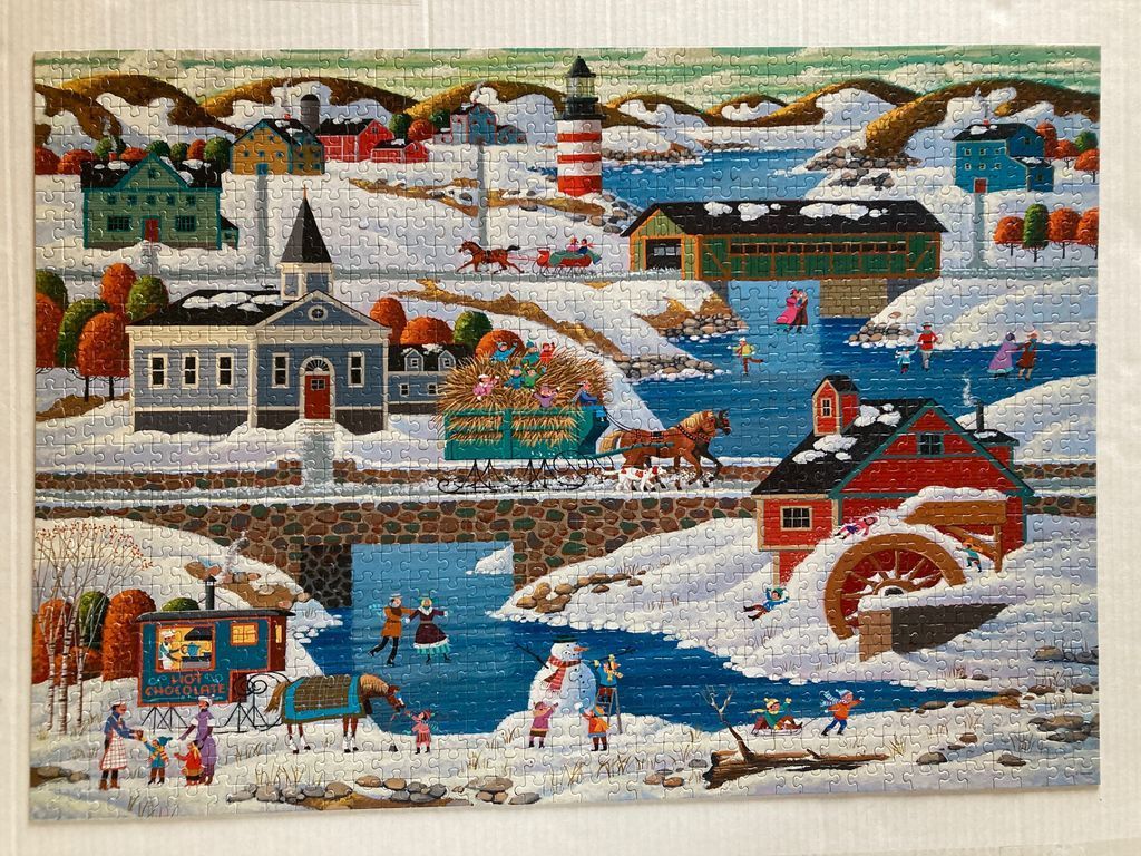A festive winter scene featuring a village, a red and white lighthouse, and people ice skating on a frozen river.