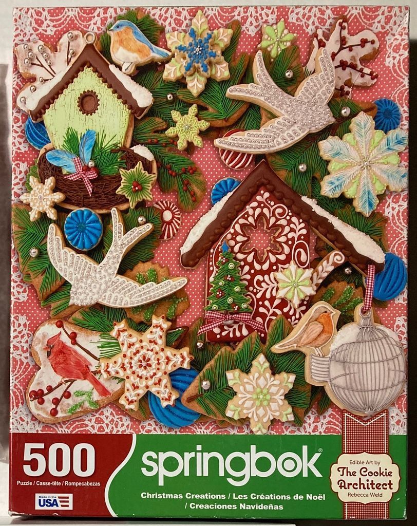 An assortment of ornate Christmas-themed cookies and sugar decorations arranged on a pink and white lace-patterned background
