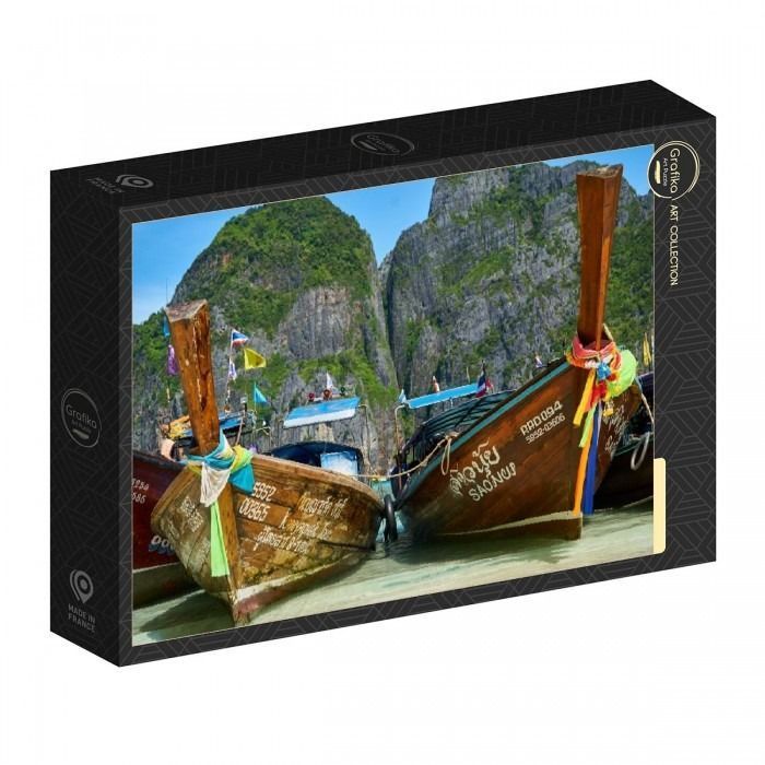 Two traditional wooden long-tail boats moored in shallow water against a backdrop of steep, jungle-covered cliffs.