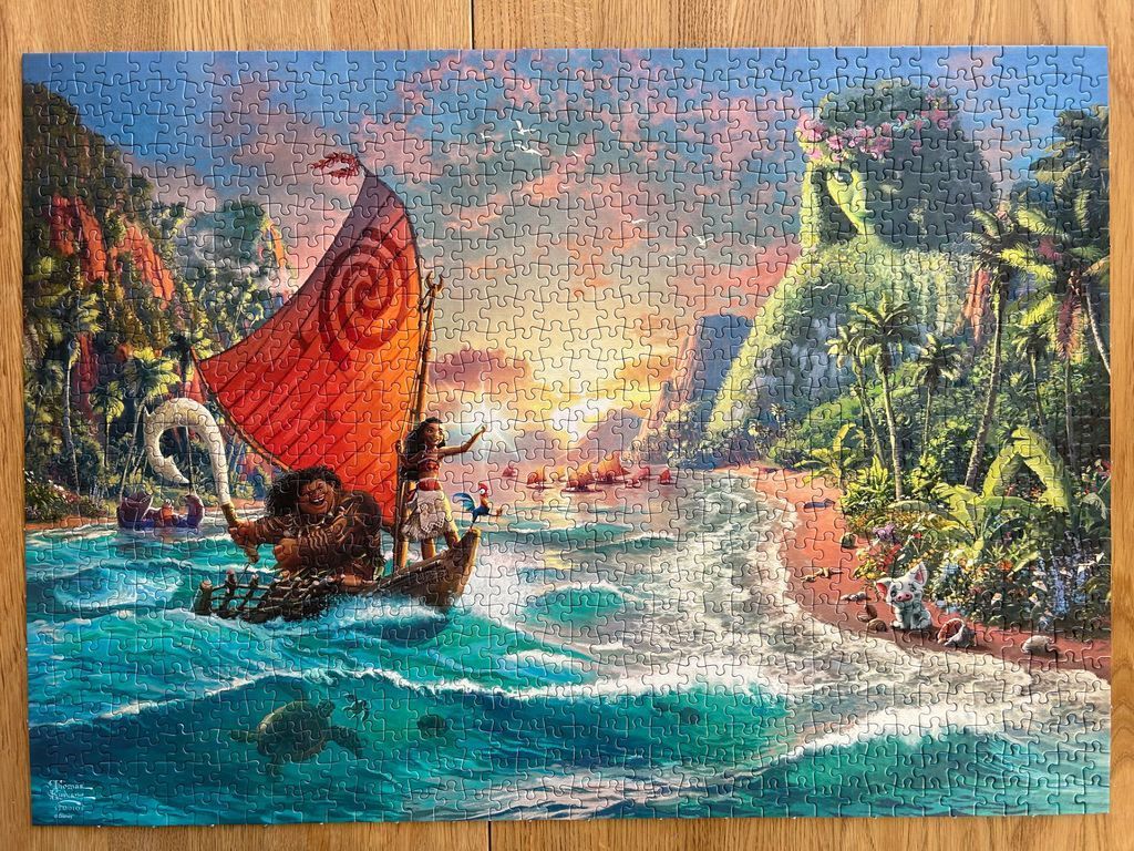 Animated scene with Moana and Maui sailing a boat toward a lush tropical island at sunset.