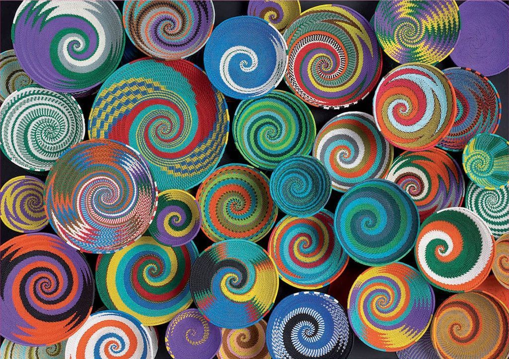 A dense cluster of colorful woven baskets with spiraling patterns set against a dark background.