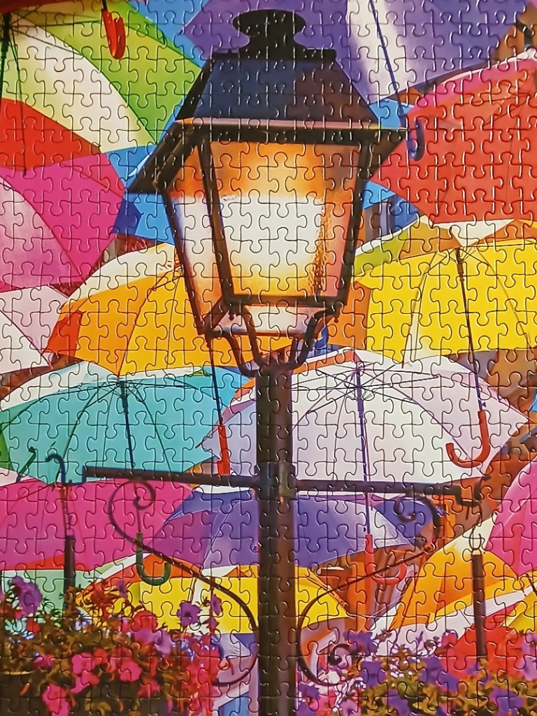 A vintage street lamp centered among a canopy of colorful, vibrant umbrellas.