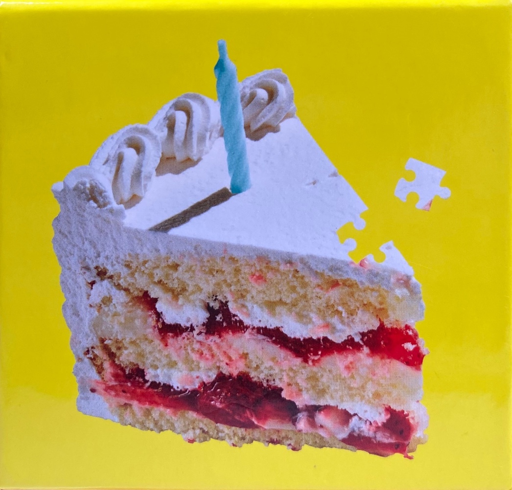 A slice of strawberry layer cake with a single blue candle against a bright yellow background.