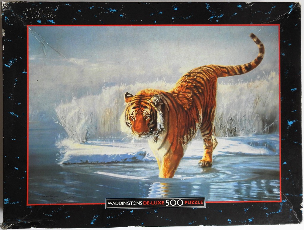 A tiger walking through shallow icy water in a snowy landscape.