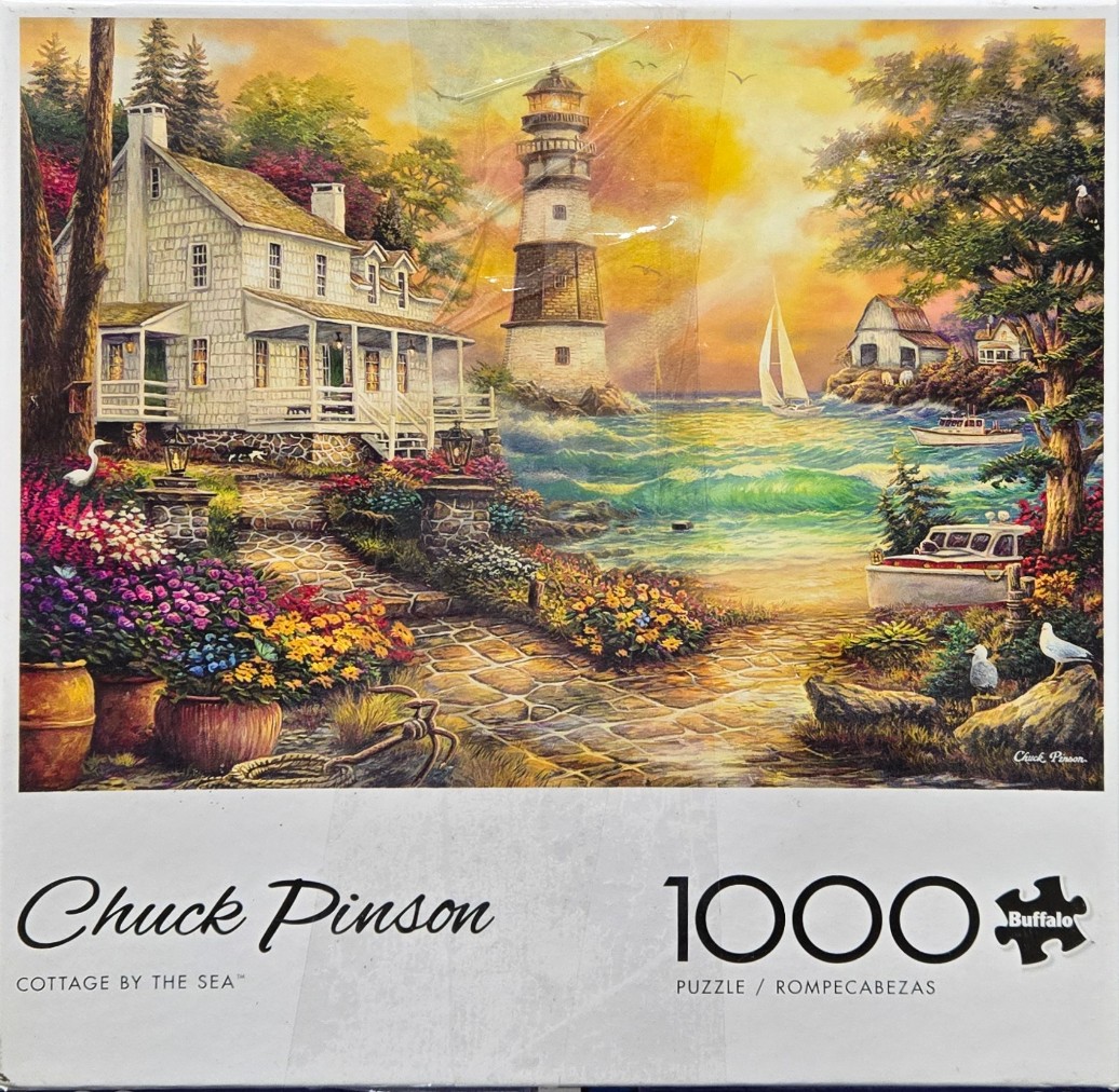 A seaside cottage with a stone path, flower gardens, a lighthouse, and sailboats at sunset.