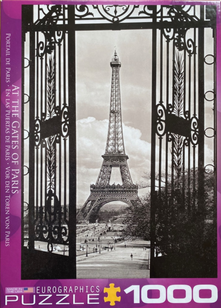 Black and white photograph of the Eiffel Tower viewed through large, ornate wrought-iron gates in Paris.