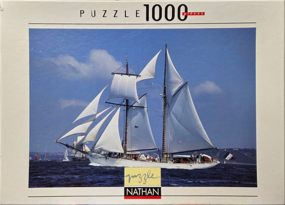 A large white two-masted schooner sailing on deep blue water under a clear sky.