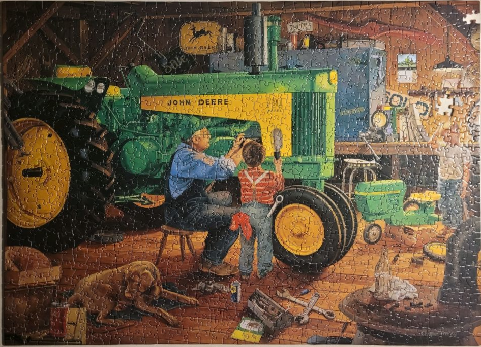 An elderly man and a young boy repairing a green and yellow tractor in a barn.