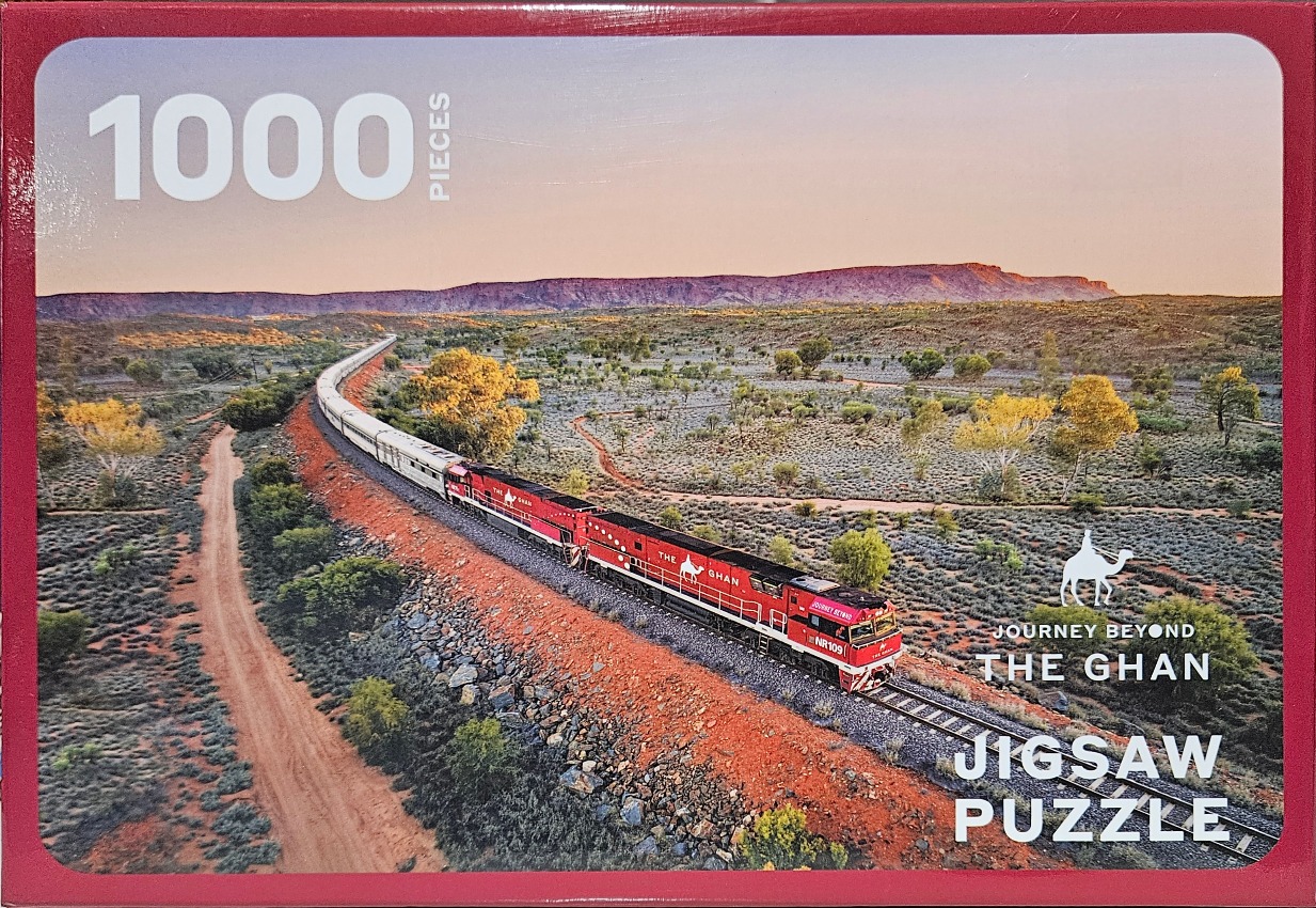 The Ghan passenger train traveling through the Australian outback at sunset.