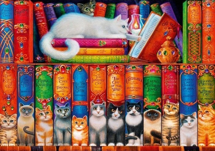 A white cat resting atop a shelf of ornate, colorful, cat-themed book spines with cats sitting in front of them.